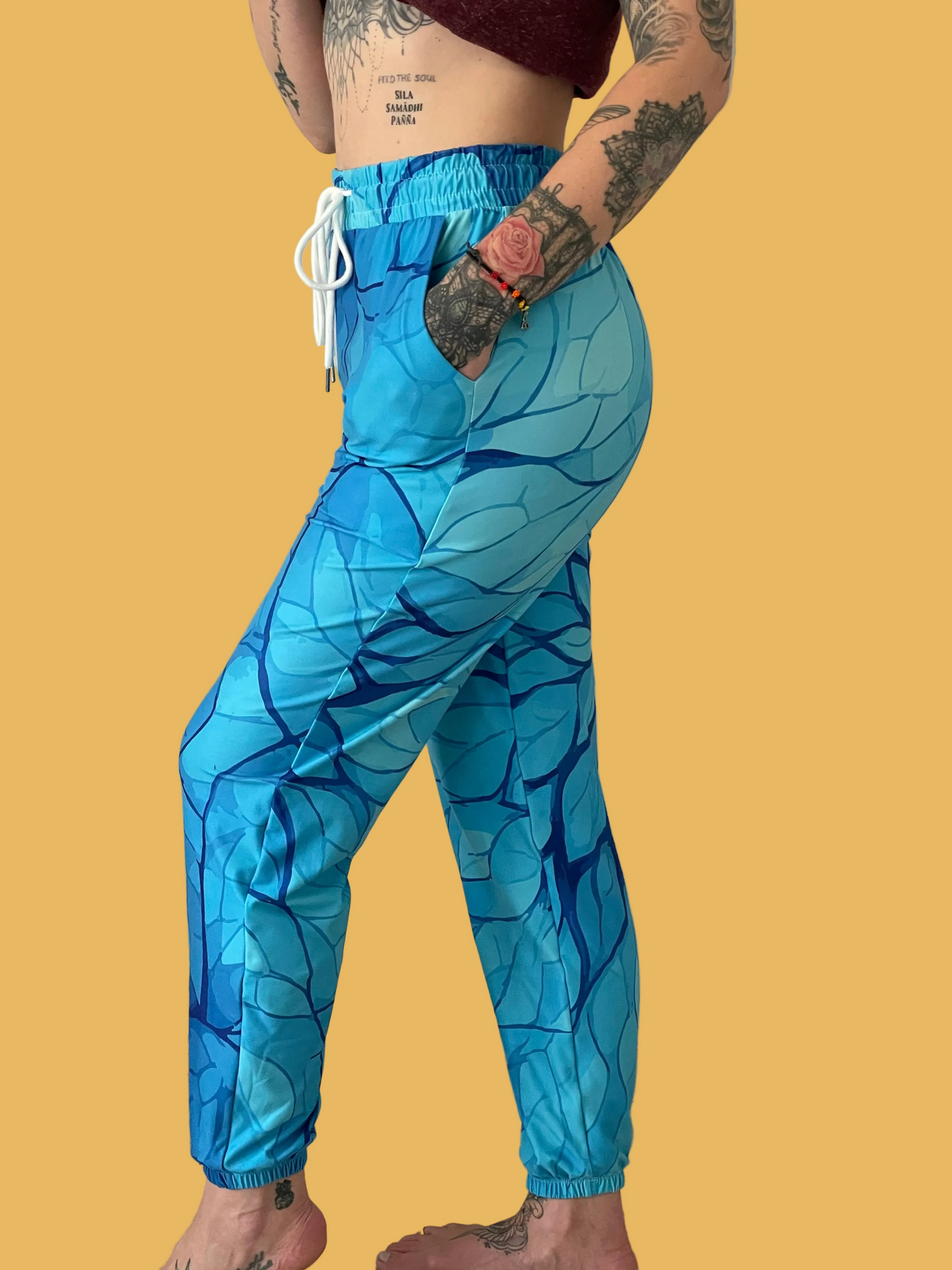 Person wearing blue leaf-patterned pants on a plain background